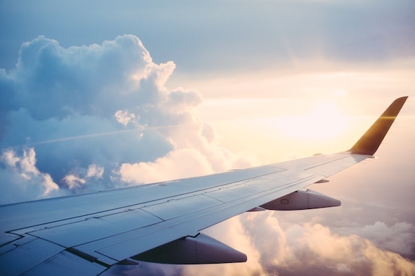 View from a flying plane with wing of the plan in foreground and sun-rising from background.